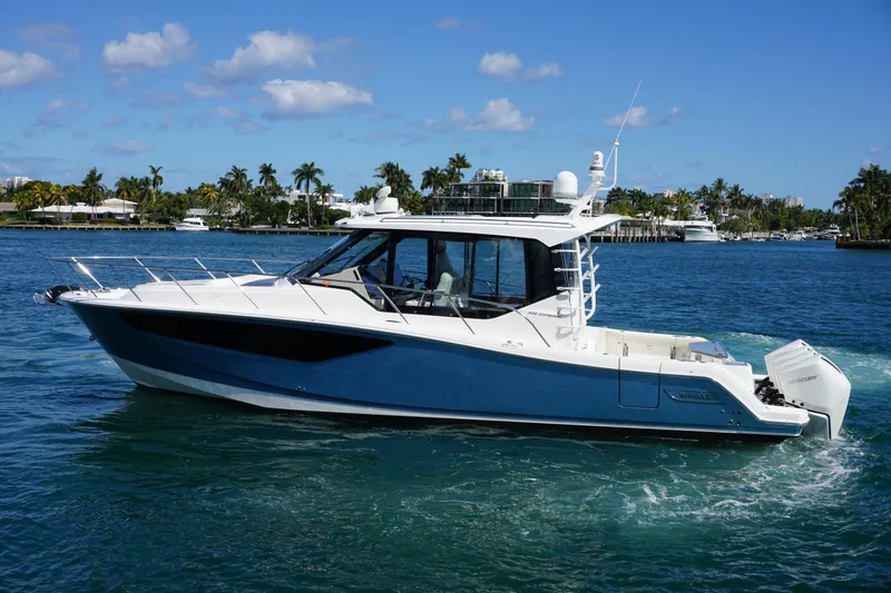 Slide: The Image of 2021 Boston Whaler 405 Conquest cruising on a sunny day with palm trees in the background. - 18