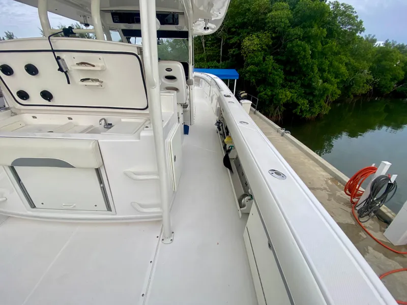 Slide: The Image of 2016 Everglades 435 Center Console boat docked near lush greenery. - 9