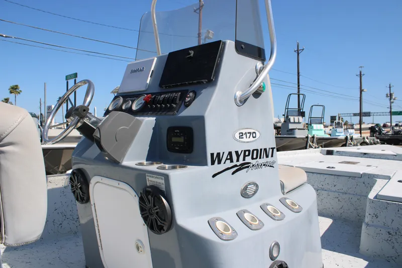 Slide: The Image of 2017 Blazer Bay 2170 boat console with steering wheel and controls, docked under clear sky. - 8