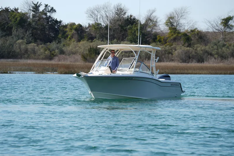 The Image of 2020 Grady-White Freedom 235 boat cruising on a serene lake with lush greenery. - 0