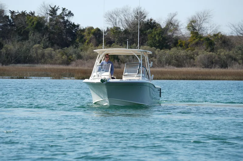 Slide: The Image of 2020 Grady-White Freedom 235 boat cruising on a serene lake with trees in the background. - 12