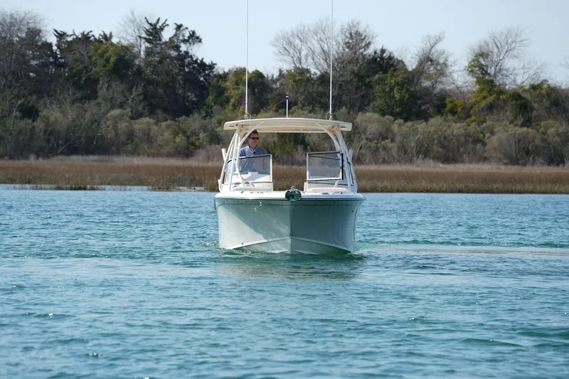 Slide: The Image of 2020 Grady-White Freedom 235 boat cruising on a serene lake with trees in the background. - 13