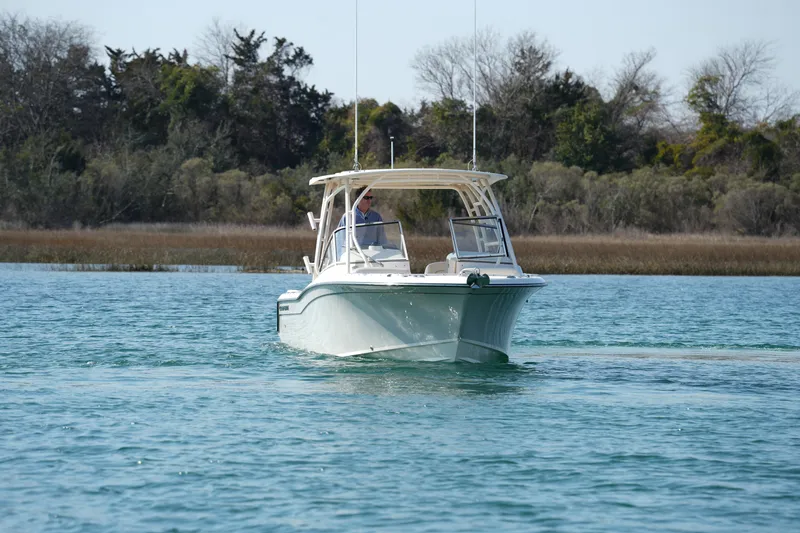 Slide: The Image of 2020 Grady-White Freedom 235 boat cruising on a serene lake with trees in the background. - 14