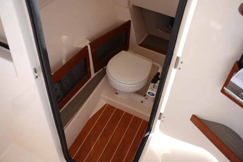 Slide: The Image of 2020 Grady-White Freedom 235 boat interior with compact marine toilet and wooden flooring. - 28