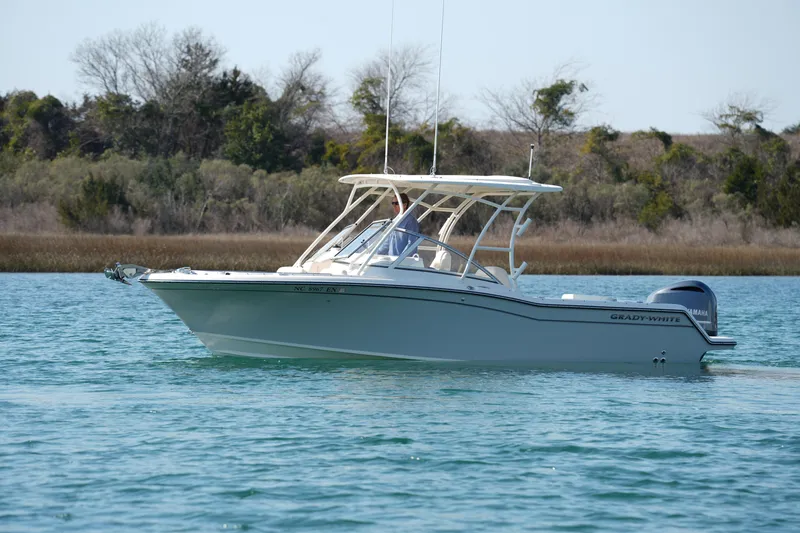 Slide: The Image of 2020 Grady-White Freedom 235 boat cruising on a serene lake with lush greenery. - 3
