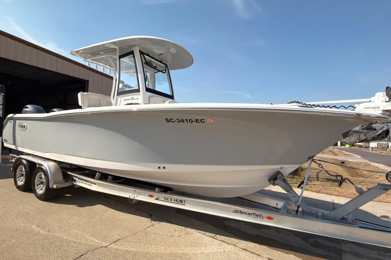Slide: The Image of 2023 Sea Hunt Gamefish 25 boat on trailer with Yamaha engine, parked outdoors. - 2