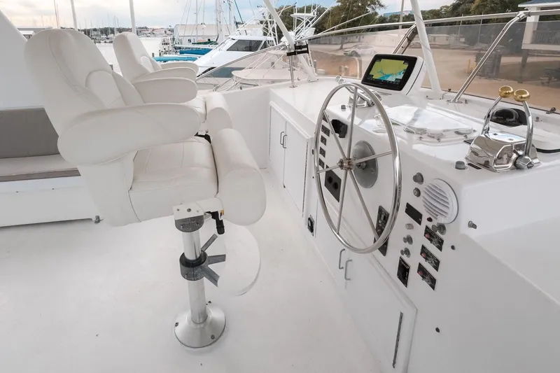 Slide: The Image of Helm of 1975 Hatteras 58 Long Range Cruiser with white captain's chairs and navigation equipment. - 16