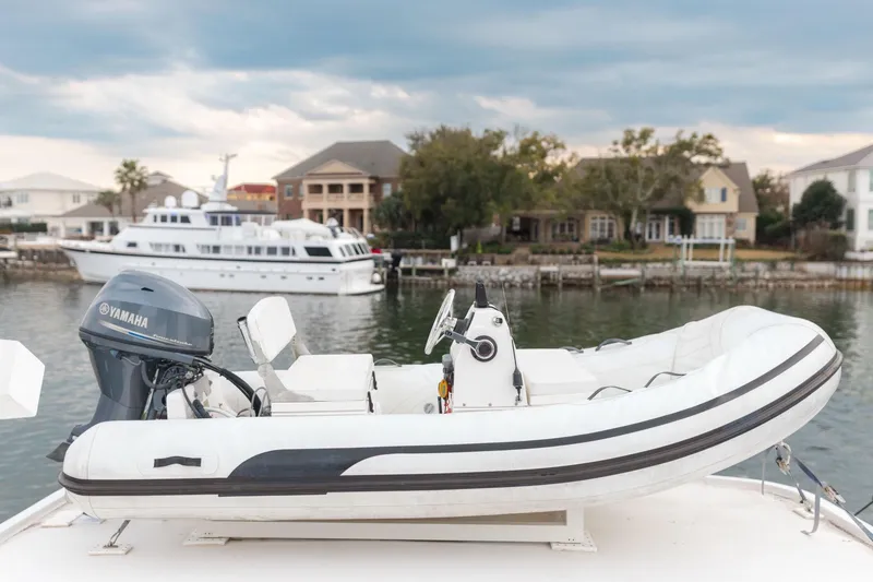 Slide: The Image of Inflatable boat with Yamaha motor on 1975 Hatteras 58 Long Range Cruiser, docked near waterfront homes. - 18