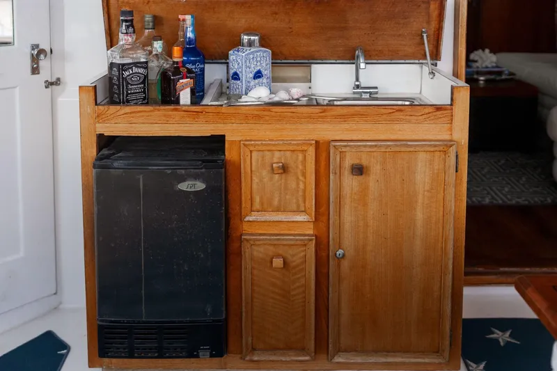 Slide: The Image of Wooden bar area with sink and mini fridge on a 1975 Hatteras 58 Long Range Cruiser. - 4