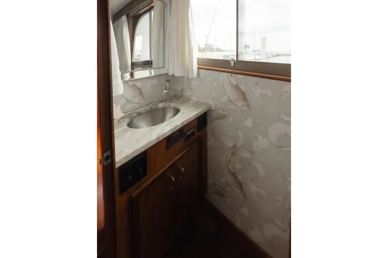 Slide: The Image of 1975 Hatteras 58 Long Range Cruiser bathroom with marble sink and nautical wallpaper. - 9