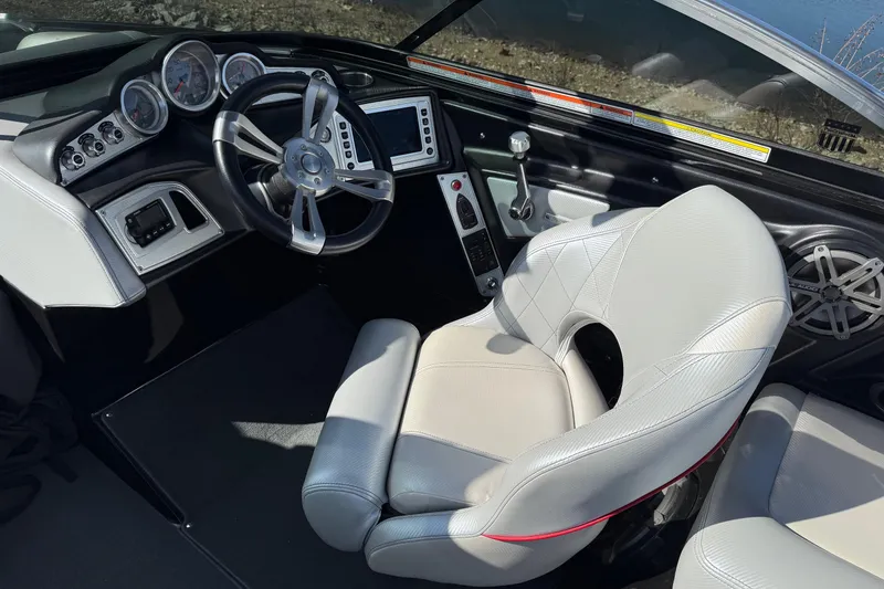 Slide: The Image of 2014 MasterCraft X30 boat interior with steering wheel, gauges, and white seating. - 13