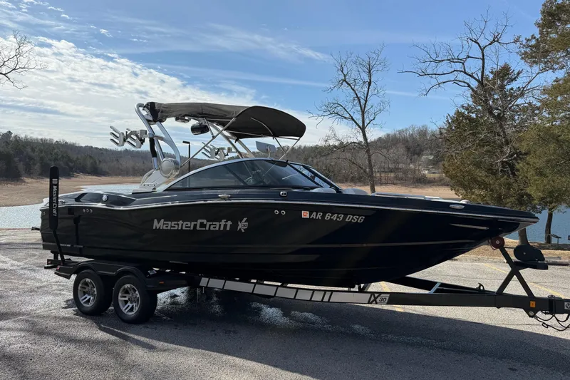 Slide: The Image of 2014 MasterCraft X30 boat on trailer by a lake, ready for adventure. - 2