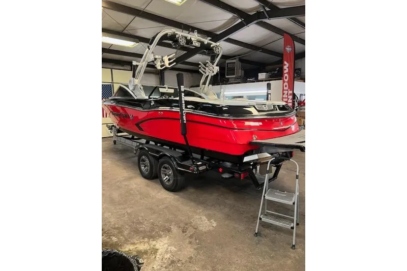 Slide: The Image of 2014 MasterCraft X30 boat in showroom, red and black, on trailer with wakeboard tower. - 28