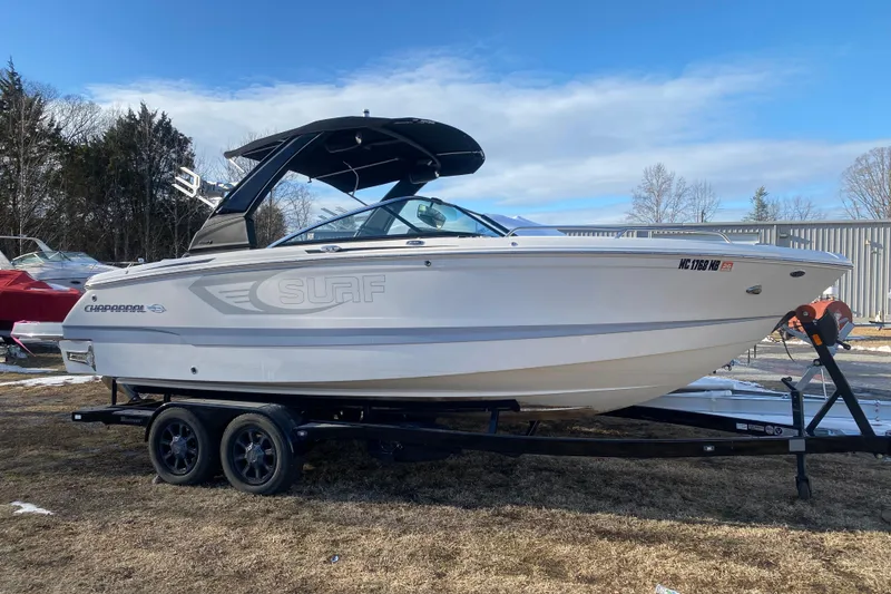 The Image of 2021 Chaparral 26 Surf boat on trailer, parked outdoors under blue sky. - 1