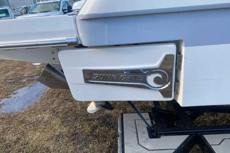 Slide: The Image of 2021 Chaparral 26 Surf boat with "Surf Gate" feature, parked on grass. - 12