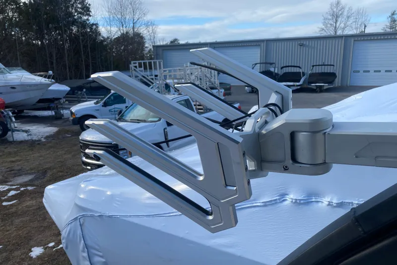 Slide: The Image of 2021 Chaparral 26 Surf boat with a sleek wakeboard rack in a marina setting. - 9