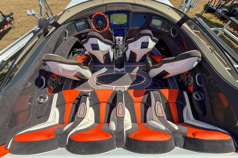 Slide: The Image of 2021 MTI 390X boat interior with red and white seating, advanced dashboard, and steering wheel. - 14