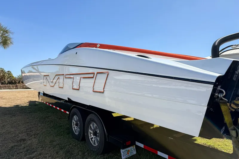 Slide: The Image of 2021 MTI 390X powerboat on trailer, sleek design, white with orange accents. - 2