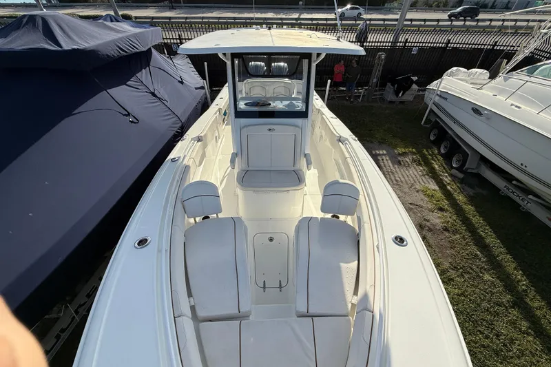 Slide: The Image of 2021 Sea Hunt Ultra 305 SE boat, white interior, docked beside covered boats. - 13