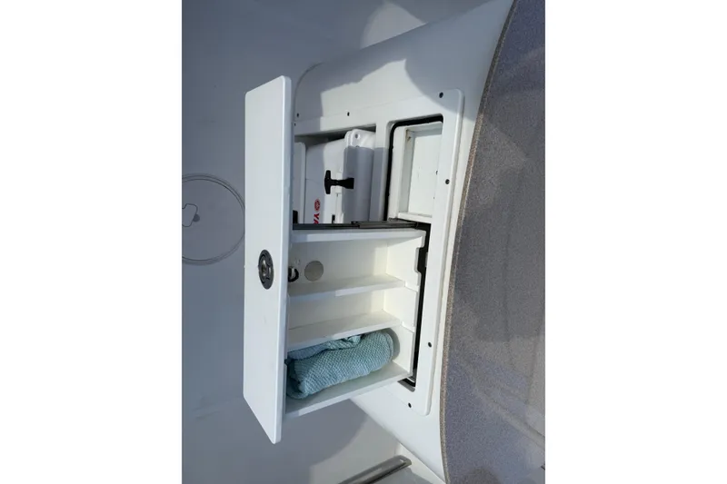 Slide: The Image of Storage compartment on a 2021 Sea Hunt Ultra 305 SE boat, featuring shelves and a towel. - 21