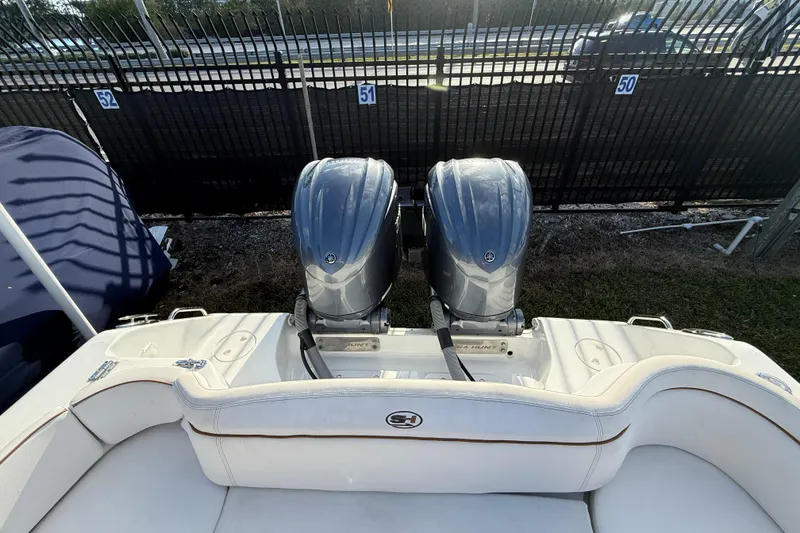 Slide: The Image of 2021 Sea Hunt Ultra 305 SE boat with dual outboard engines, parked near a fence. - 9