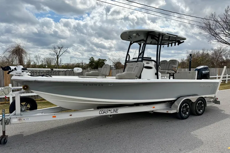 The Image of 2021 Sea Pro 248 Bay boat on trailer, parked outdoors under cloudy sky. - 1