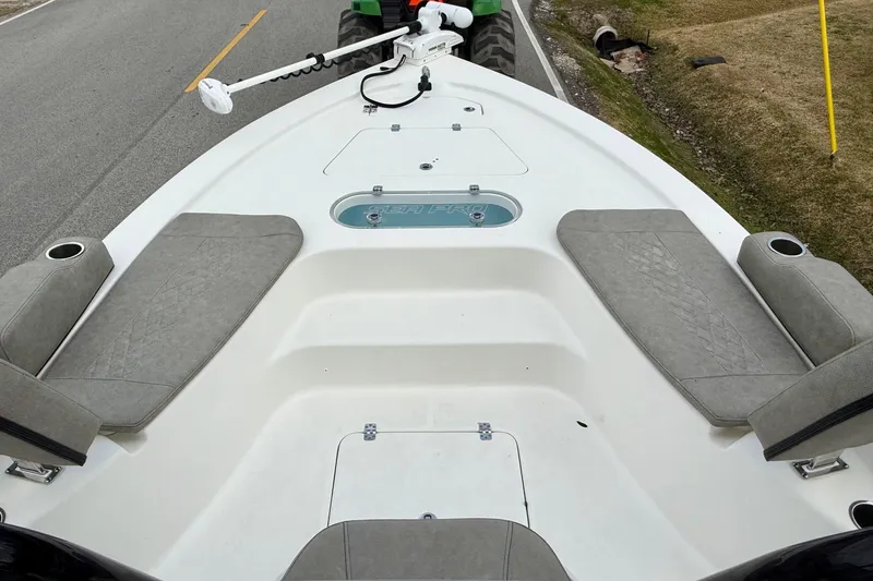 Slide: The Image of 2021 Sea Pro 248 Bay boat interior with seating and trolling motor on a road. - 14