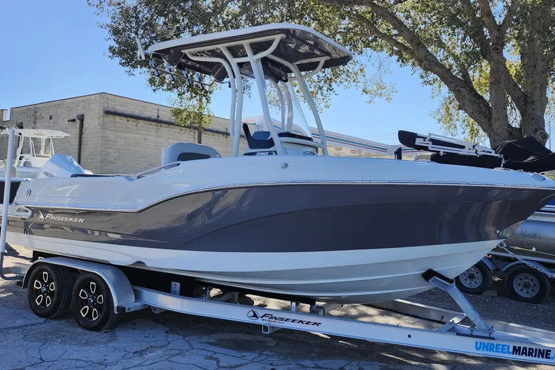 Slide: The Image of 2022 Finseeker 230 CC boat on trailer, parked outdoors under a tree. - 7