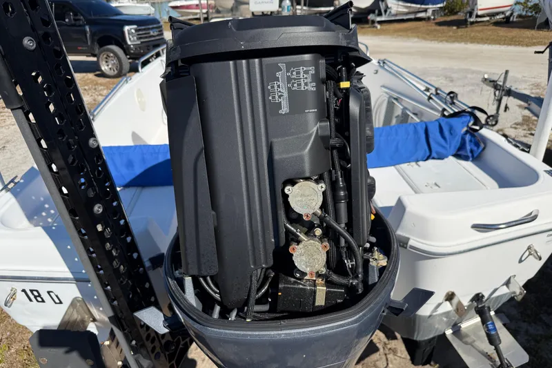 Slide: The Image of 2002 Cobia 191 Bay boat with exposed engine, parked outdoors. - 13