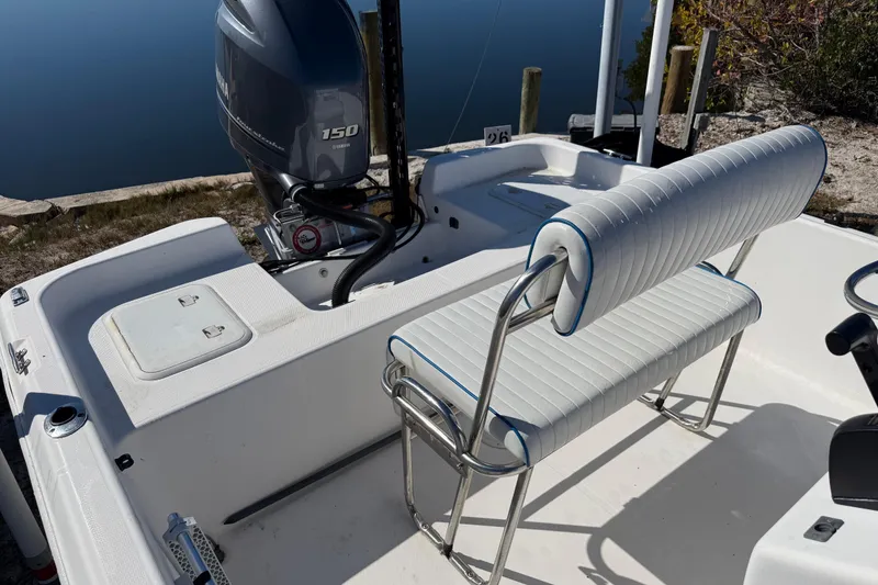 Slide: The Image of 2002 Cobia 191 Bay boat with Yamaha 150 engine, white seating, docked by calm water. - 27