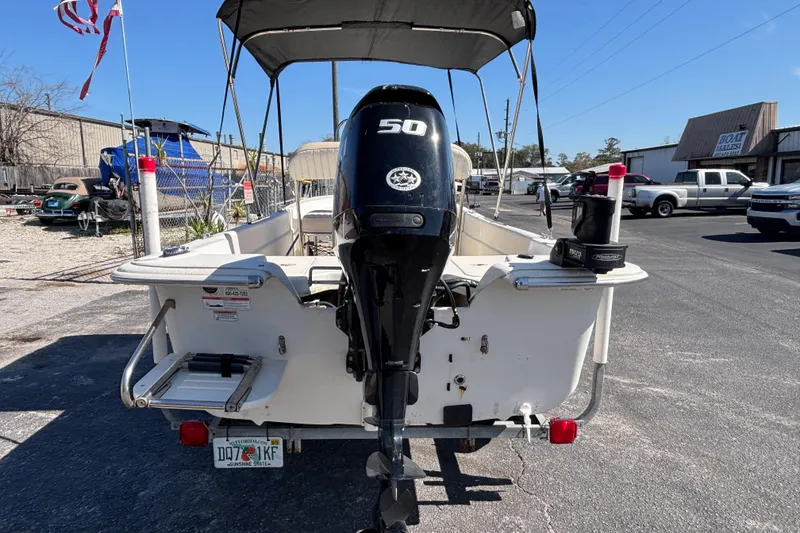 Slide: The Image of 2016 Carolina Skiff 16 JVX CC boat with outboard motor and canopy in parking lot. - 8