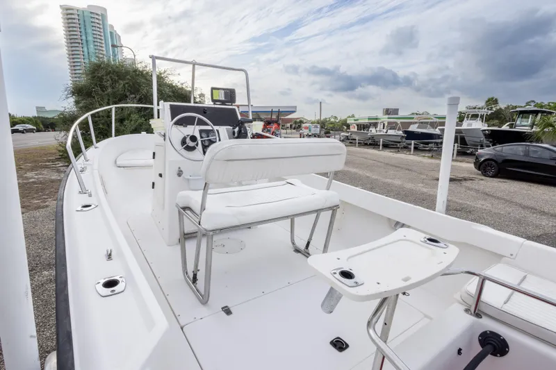 Slide: The Image of 1999 Boston Whaler Outrage 17 boat with white interior, parked near modern buildings. - 29