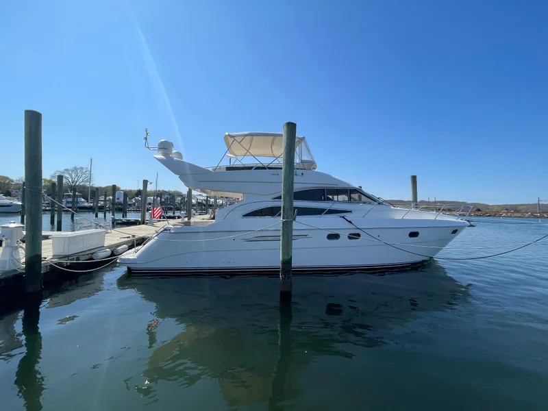 The Image of 2005 Viking Princess 50 Flybridge yacht docked in a marina under clear blue skies. - 0