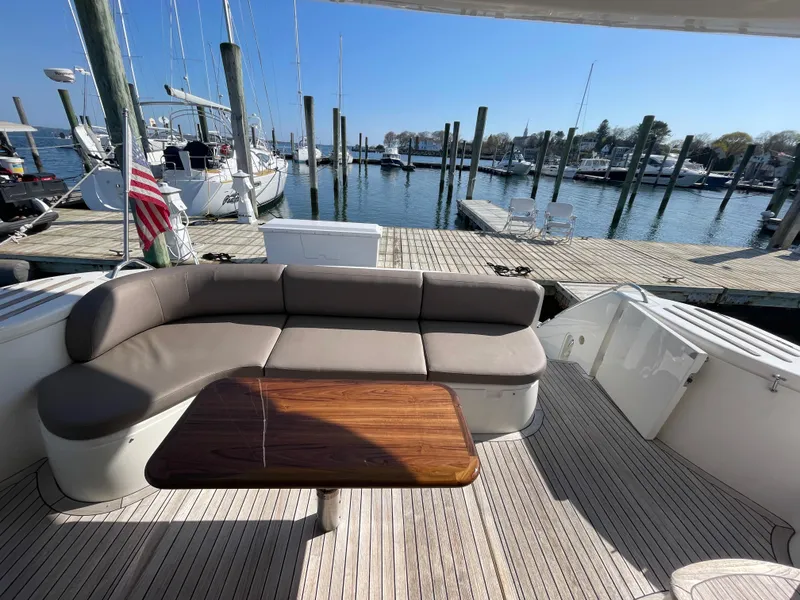 Slide: The Image of 2005 Viking Princess 50 Flybridge yacht with dockside view, featuring a cushioned seating area and wooden table. - 5