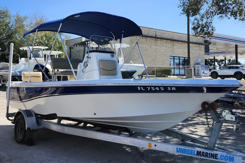 The Image of 2020 NauticStar 195 NauticBay boat on trailer, blue canopy, parked outdoors. - 1