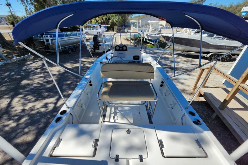 Slide: The Image of 2020 NauticStar 195 NauticBay boat with blue canopy and seating, docked outdoors. - 28