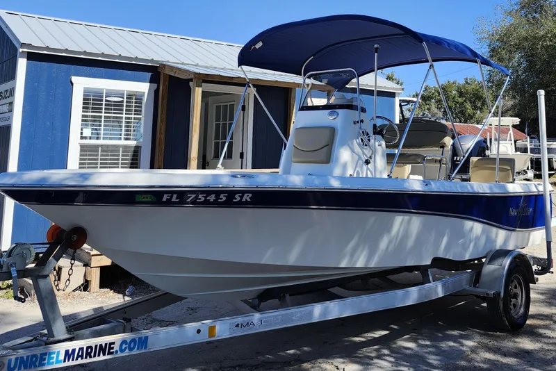 Slide: The Image of 2020 NauticStar 195 NauticBay boat on trailer with blue canopy, parked outside. - 3