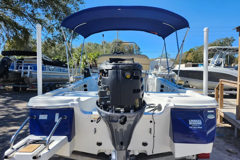 Slide: The Image of 2020 NauticStar 195 NauticBay boat with outboard motor and blue canopy in a marina. - 40