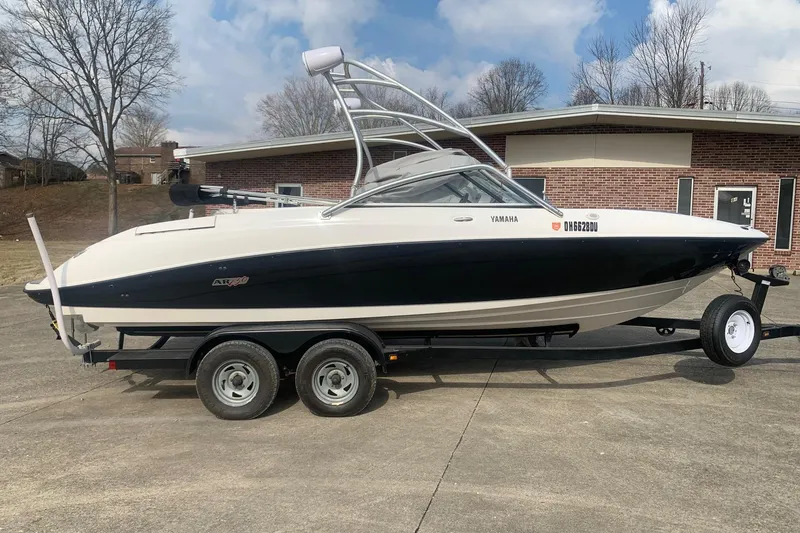 The Image of 2004 Yamaha Boats AR230 on trailer, parked outdoors near a brick building. - 0