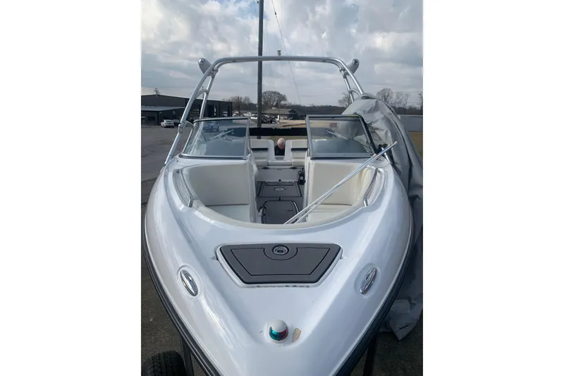 Slide: The Image of 2004 Yamaha Boats AR230, sleek white design, open bow, parked outdoors under cloudy sky. - 3