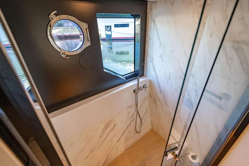 Slide: The Image of Luxurious bathroom on 2023 Absolute 64 Navetta yacht with marble walls and porthole window. - 30
