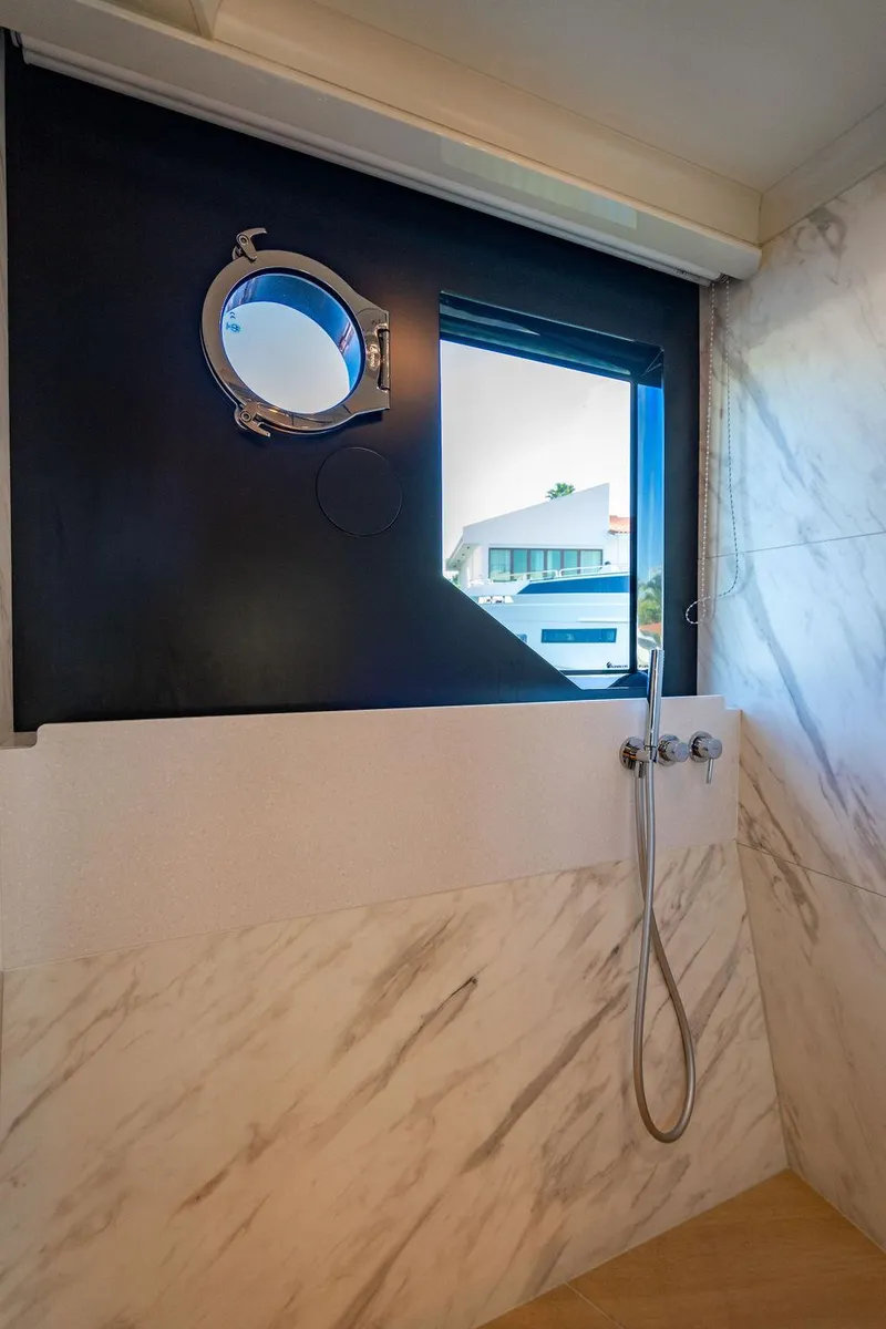 Slide: The Image of Luxurious bathroom on 2023 Absolute 64 Navetta yacht with marble walls and porthole window. - 31