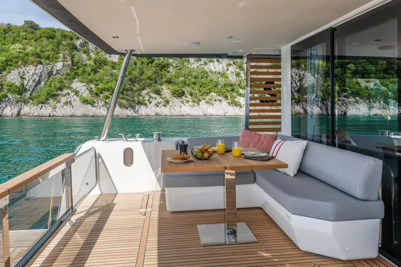 Slide: The Image of 2026 Beneteau Grand Trawler 62 deck with seating, table, and scenic water view. - 3