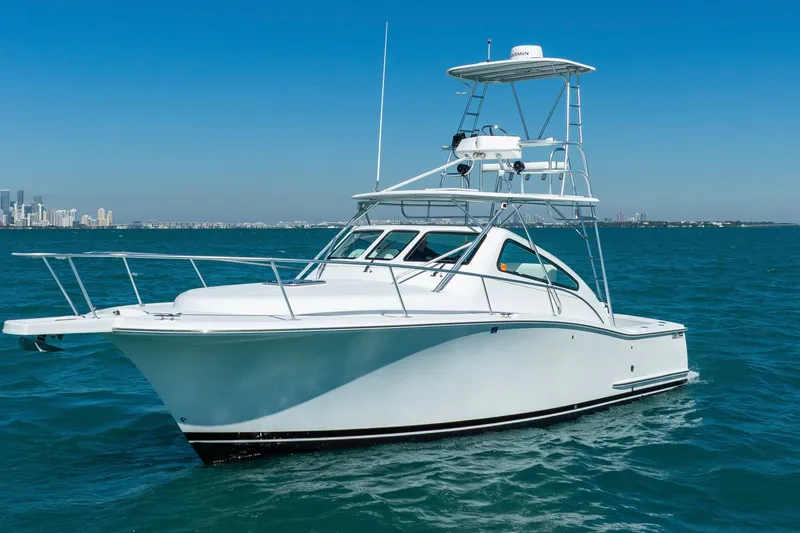 The Image of 2004 Luhrs 32 Open boat cruising on blue ocean near city skyline. - 0