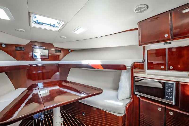 Slide: The Image of 2004 Luhrs 32 Open cabin interior with wood finish, dining area, and kitchenette. - 38