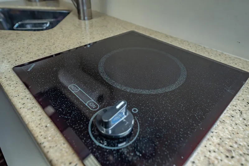 Slide: The Image of 2004 Luhrs 32 Open yacht kitchen with sleek electric cooktop on speckled countertop. - 40