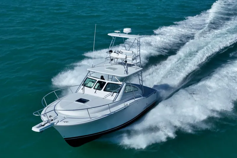Slide: The Image of 2004 Luhrs 32 Open boat cruising on clear blue water, creating a dynamic wake. - 52