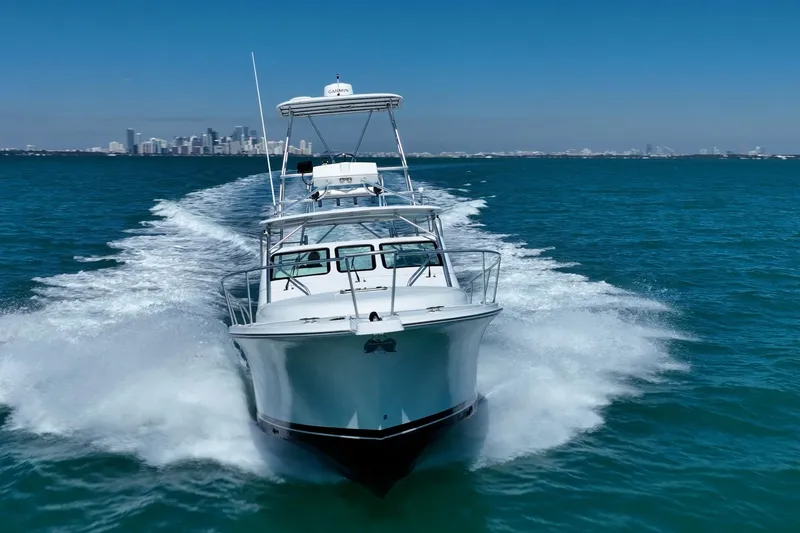 Slide: The Image of 2004 Luhrs 32 Open yacht cruising on blue ocean with city skyline in background. - 53