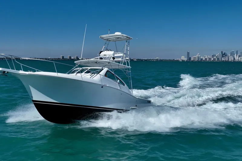 Slide: The Image of 2004 Luhrs 32 Open boat cruising on blue ocean near city skyline. - 59