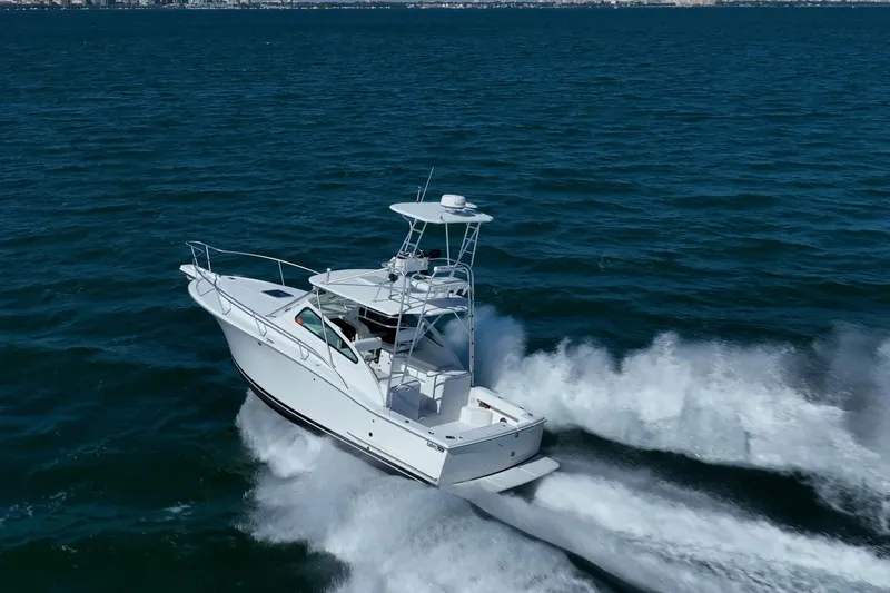 Slide: The Image of 2004 Luhrs 32 Open boat cruising on open water, creating a dynamic wake. - 68